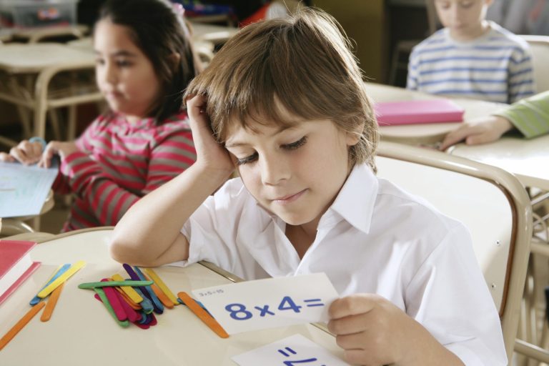 Ein Junge bekommt Mathe-Nachhilfe und betrachtet konzentriert eine Karte mit einer Rechenaufgabe.